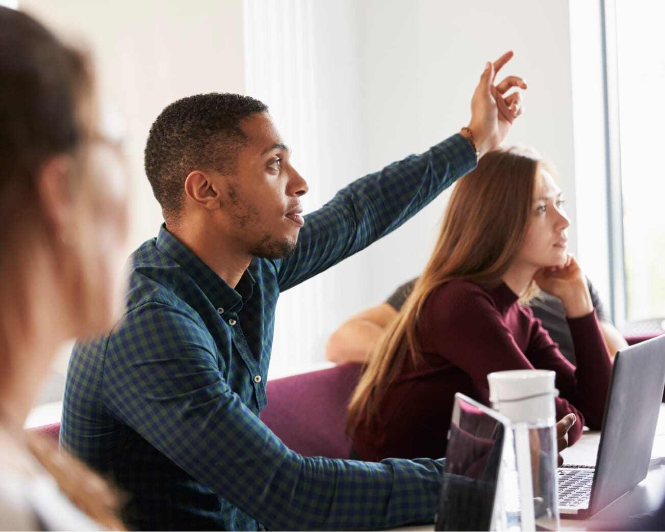 man raising hand to ask question in a classroom setting